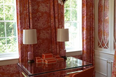 Diseño de despacho tradicional de tamaño medio sin chimenea con parades naranjas, suelo de madera en tonos medios, escritorio independiente y suelo marrón