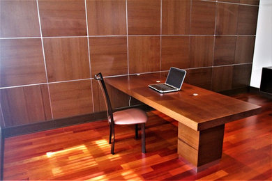 Foto de despacho actual de tamaño medio con biblioteca, suelo de madera oscura y escritorio empotrado