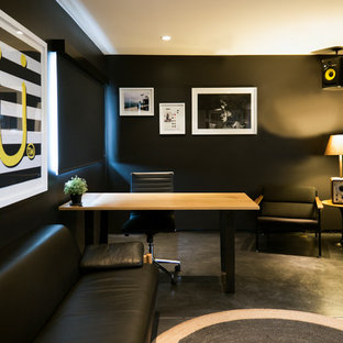 Cette photo montre un bureau éclectique de taille moyenne et de type studio avec un mur noir, béton au sol, un bureau indépendant et un sol noir.