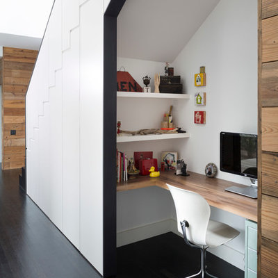Trendy built-in desk dark wood floor study room photo in Austin with white walls