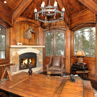 Cette image montre un bureau chalet avec un sol en bois foncé, une cheminée d'angle et un bureau indépendant.