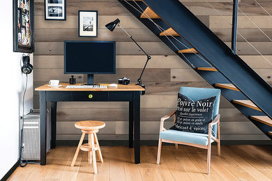 Modelo de despacho minimalista de tamaño medio con paredes grises, suelo de madera clara, escritorio independiente y suelo marrón