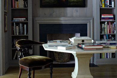 Mittelgroßes Klassisches Lesezimmer mit grauer Wandfarbe, braunem Holzboden, Kamin, Kaminumrandung aus Holz, freistehendem Schreibtisch und braunem Boden in Toronto