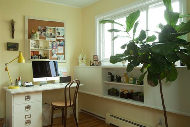 Ejemplo de despacho tradicional de tamaño medio con paredes amarillas, suelo de madera clara y escritorio independiente