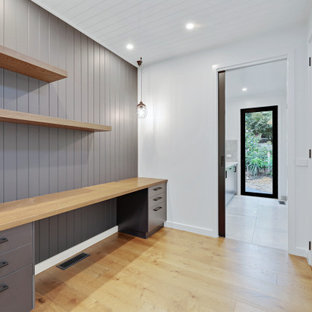 Modernes Arbeitszimmer ohne Kamin mit Arbeitsplatz, weißer Wandfarbe, Einbau-Schreibtisch, braunem Boden und Holzdielendecke in Sonstige