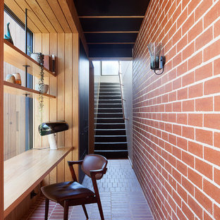 Mid-Century Arbeitszimmer mit roter Wandfarbe, Backsteinboden, Einbau-Schreibtisch und rotem Boden in Melbourne