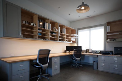 Imagen de despacho de estilo americano extra grande con paredes blancas, suelo de cemento y escritorio empotrado