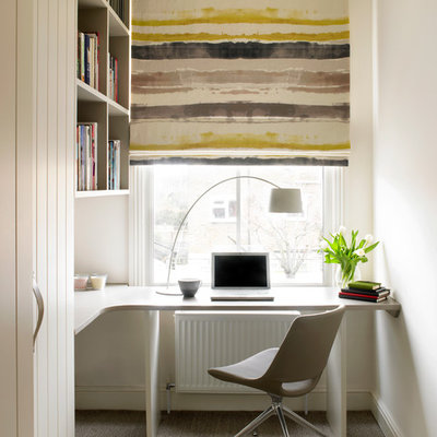 Home office - contemporary built-in desk carpeted and beige floor home office idea in London with white walls