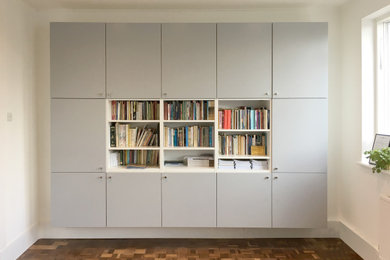Diseño de despacho moderno de tamaño medio con paredes blancas, suelo de madera oscura y suelo marrón
