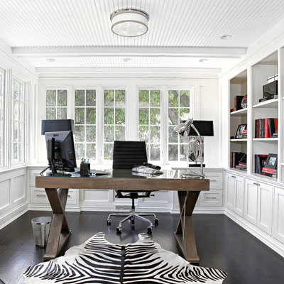Elegant freestanding desk dark wood floor and black floor home office photo in New York with white walls