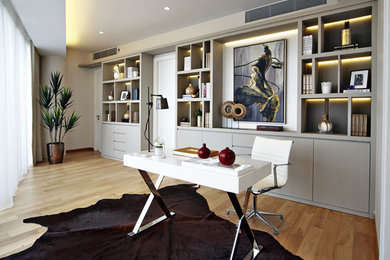Diseño de despacho actual sin chimenea con suelo de madera en tonos medios y escritorio independiente