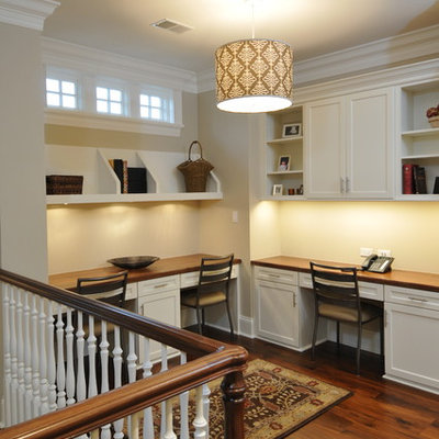 Elegant built-in desk dark wood floor home office photo in Chicago with beige walls