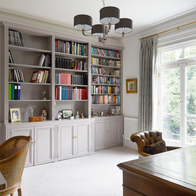 Elegant freestanding desk carpeted and gray floor home office photo in London with white walls