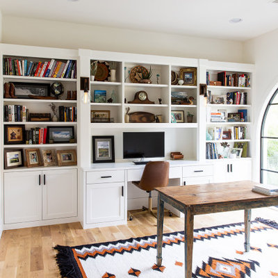 Tuscan freestanding desk medium tone wood floor and brown floor home office photo in Dallas with beige walls