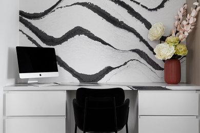 Exemple d'un bureau tendance de taille moyenne et de type studio avec un mur blanc, un bureau intégré, un sol marron et du papier peint.