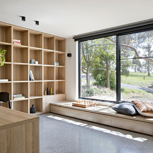 Foto på ett mellanstort funkis hemmabibliotek, med flerfärgade väggar, betonggolv och ett inbyggt skrivbord