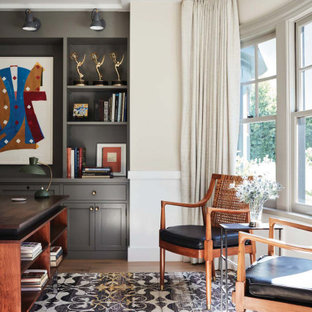Klassisches Arbeitszimmer mit beiger Wandfarbe, dunklem Holzboden, freistehendem Schreibtisch, braunem Boden und vertäfelten Wänden in Los Angeles