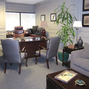 Cette photo montre un bureau chic de taille moyenne avec un mur gris, moquette, une cheminée standard, un bureau indépendant, un manteau de cheminée en bois et un sol gris.