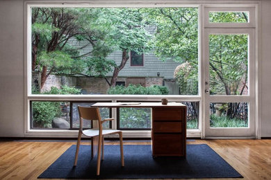 シカゴにある中くらいなコンテンポラリースタイルのおしゃれなホームオフィス・書斎 (白い壁、淡色無垢フローリング、自立型机) の写真