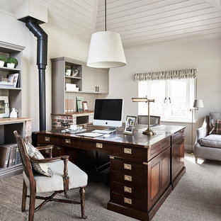 Inredning av ett klassiskt hemmabibliotek, med vita väggar, heltäckningsmatta, en öppen vedspis och ett fristående skrivbord