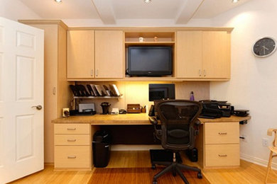 Example of a mid-sized built-in desk light wood floor home office design in Other with white walls