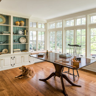 Mittelgroßes Klassisches Arbeitszimmer ohne Kamin mit braunem Holzboden, freistehendem Schreibtisch, Arbeitsplatz, orangem Boden und beiger Wandfarbe in Philadelphia