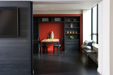 Modelo de despacho contemporáneo de tamaño medio con paredes rojas, suelo de madera oscura y escritorio independiente