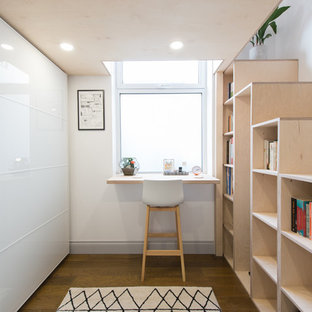 Idee per uno studio nordico con libreria, pareti bianche, parquet scuro, nessun camino, scrivania incassata e pavimento marrone