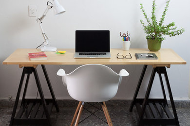 Modelo de despacho contemporáneo de tamaño medio con paredes blancas, escritorio empotrado y suelo de cemento