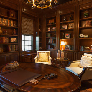 Mittelgroßes Klassisches Arbeitszimmer ohne Kamin mit Arbeitsplatz, brauner Wandfarbe, dunklem Holzboden und freistehendem Schreibtisch in Houston