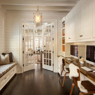 Mid-sized elegant built-in desk dark wood floor study room photo in New York with white walls