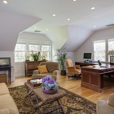 Large elegant built-in desk medium tone wood floor home office photo in New York with white walls