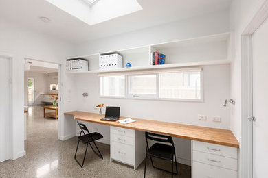 メルボルンにあるお手頃価格の小さなコンテンポラリースタイルのおしゃれなホームオフィス・書斎 (ライブラリー、白い壁、コンクリートの床、造り付け机、グレーの床) の写真