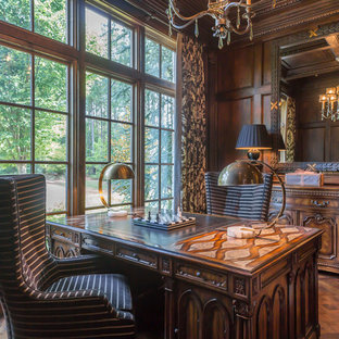 Großes Mediterranes Arbeitszimmer mit Arbeitsplatz, brauner Wandfarbe, braunem Holzboden, freistehendem Schreibtisch, Kamin und Kaminumrandung aus Stein in Atlanta