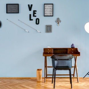 Mittelgroßes Modernes Arbeitszimmer ohne Kamin mit Arbeitsplatz, blauer Wandfarbe, braunem Holzboden, freistehendem Schreibtisch und beigem Boden in Berlin