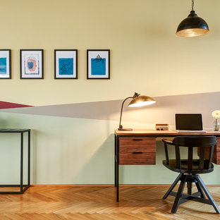 Mittelgroßes Modernes Arbeitszimmer ohne Kamin mit Arbeitsplatz, bunten Wänden, hellem Holzboden, freistehendem Schreibtisch und beigem Boden in Berlin