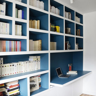 Photo of a contemporary home office in Other with white walls, medium hardwood flooring, a built-in desk and brown floors.