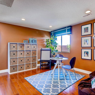 Cette photo montre un bureau chic avec un mur orange, un sol en bois brun, aucune cheminée et un bureau indépendant.