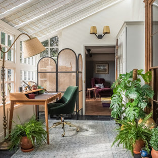Inspiration för mellanstora eklektiska hemmabibliotek, med skiffergolv, svart golv, vita väggar och ett fristående skrivbord