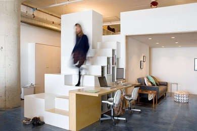 Home studio - industrial built-in desk concrete floor home studio idea in Los Angeles with white walls