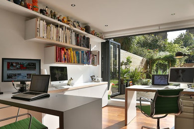 This is an example of a medium sized eclectic home studio in London with white walls, dark hardwood flooring and a freestanding desk.