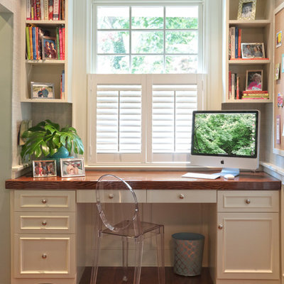 Example of a classic built-in desk medium tone wood floor home office design in Other with white walls