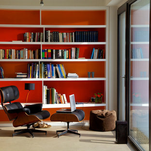Inredning av ett modernt arbetsrum, med ett bibliotek, orange väggar och beiget golv