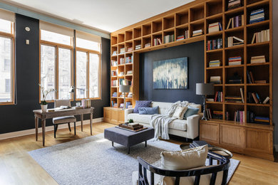Diseño de despacho clásico grande con paredes azules, suelo de madera clara y escritorio independiente