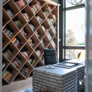 Modernes Arbeitszimmer mit schwarzer Wandfarbe, braunem Holzboden, freistehendem Schreibtisch und braunem Boden in Dallas