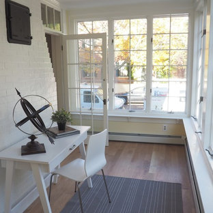 Großes Klassisches Arbeitszimmer mit Arbeitsplatz, gelber Wandfarbe, braunem Holzboden und freistehendem Schreibtisch in Boston