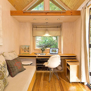 Kleines Modernes Arbeitszimmer ohne Kamin mit braunem Holzboden, Arbeitsplatz, beiger Wandfarbe und Einbau-Schreibtisch in Los Angeles