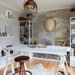 Cette image montre un bureau bohème de taille moyenne et de type studio avec un mur gris, un sol en bois clair, aucune cheminée, un bureau indépendant, du papier peint et un sol beige.