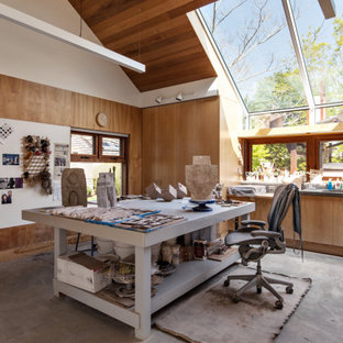 Example of a trendy freestanding desk concrete floor, gray floor, vaulted ceiling and wood wall home studio design in New York with brown walls