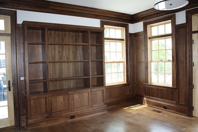 Foto de despacho clásico de tamaño medio con biblioteca, paredes blancas, suelo de madera en tonos medios y suelo marrón